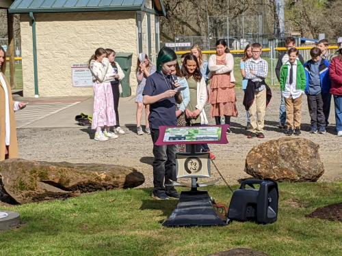 A child stands behind an informational pedestal and addresses the crowd